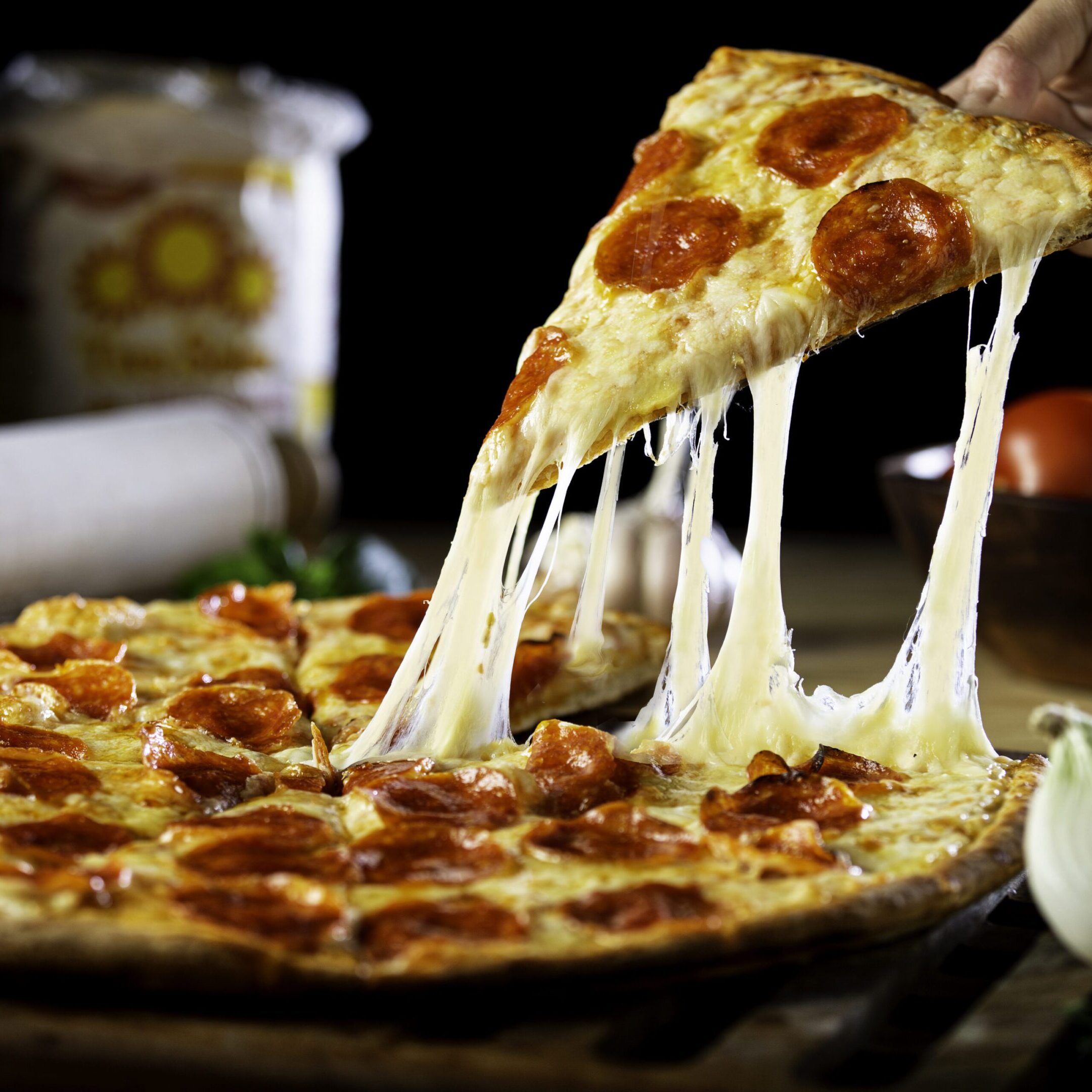 Person getting a piece of cheesy pepperoni pizza Cheesy pepperoni pizza slice being lifted.